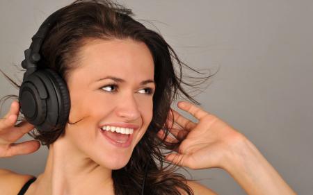 Девушка брюнетка слушает музыку в отличном настроение