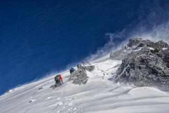 Альпинисты взбираются на крутую снежную гору, зима